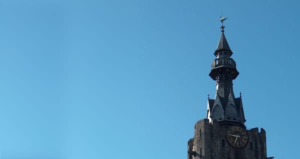 Haut du beffroi avant sa restauration sous un ciel bleu. on aperçoit le campanile et Beffy à son sommet ainsi que l'horloge.
